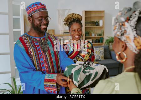 Uomo Nero sorridente e donna che donano un regalo avvolto durante la celebrazione di Kwanzaa Foto Stock