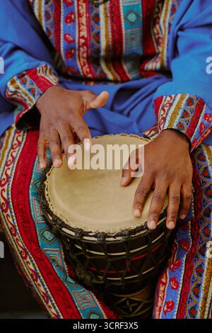 Adulto nero che suona la batteria durante la celebrazione Kwanzaa con abbigliamento tradizionale Foto Stock