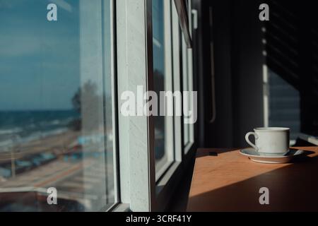 una tazza di caffè caldo sul tavolo la mattina, tempo di relax, vicino alla finestra Foto Stock