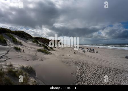 Reise auf die Insel Sylt. Blick a Kampen am Weststrand vom der Holz-Plattform am Roten Kliff aus hinab auf den Strand. DAS Bild zeigt links die Dünen, am Strand Strandkörbe bei strammem Wind die aufgewühlte Nordsee. Wolken vervollständigen das Szenario. Nordfriesland Schleswig-Holstein Deutschland *** gita all'isola di Sylt View a Kampen sulla spiaggia ovest dalla piattaforma di legno sulla Red Cliff fino alla spiaggia l'immagine mostra le dune sulla sinistra, le sdraio sulla spiaggia in un forte vento le nuvole del Mare del Nord completano lo scenario North Frisia Schleswig Holstein Germania Foto Stock