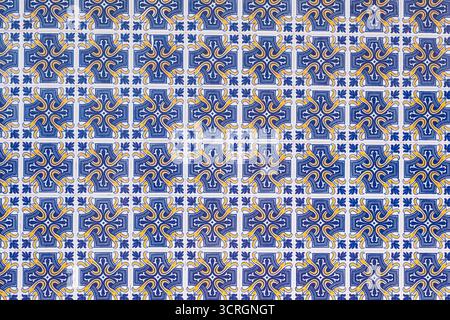 Le piastrelle decorative in ceramica blu e gialla formano un motivo ornamentale ripetuto su una parete. Foto Stock