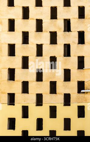 Parete geometrica illuminata dal sole con finestre rettangolari incassate in Una ripetizione a griglia regolare Foto Stock