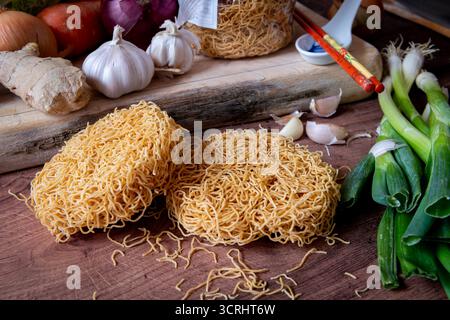 Spaghetti di grano fine cinesi essiccati su un piano di lavoro in cucina insieme a varie verdure. Foto Stock