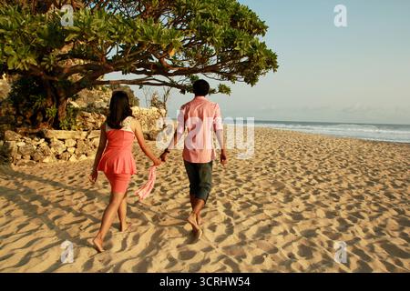 Un paio di amanti trascorrono il pomeriggio camminando sulla sabbia bianca della spiaggia di Pok Tunggal, Gunungkidul. Foto Stock