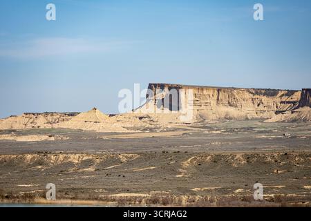 Paesaggio arido con formazioni di arenaria erose sotto un cielo azzurro dalle Bardenas Reales, Spagna Foto Stock