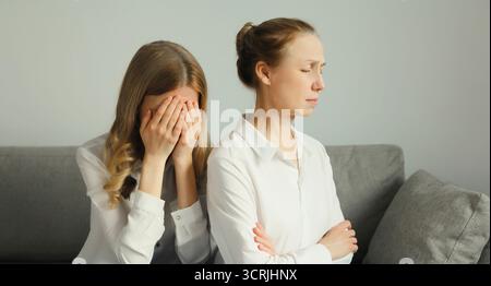 Sconvolta ha offeso due donne caucasiche, madre o sorella matura e figlia adulta che piangono insieme sedute sul divano a casa Foto Stock