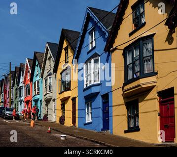 COBH, IRLANDA - 15 agosto 2025: La vivace fila di case in pendenza conosciuta come "Deck of Cards" mette in mostra il fascino di Cobh e rimane una delle mete preferite dai fotografi Foto Stock