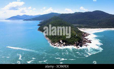 Vista aerea della costa rocciosa e montuosa della spiaggia di Naufragados a Florianópolis, Santa Catarina, piena di vegetazione forestale atlantica. Foto Stock