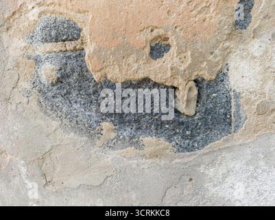 Primo piano gravemente danneggiato e staccato la parete azzurra, rivelando un grande foro nell'intonaco che espone il calcestruzzo sottostante. Concentratevi sui livelli Foto Stock