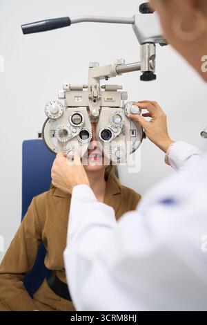 Paziente sottoposto a esame oculistico utilizzando il phoropter in clinica Foto Stock