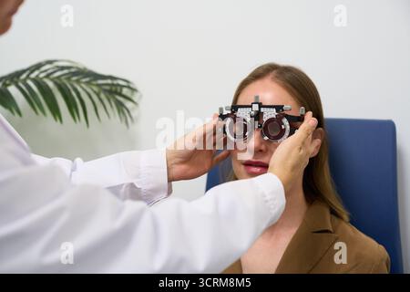 Optometrista che esegue l'esame oculare utilizzando il phoropter sul paziente Foto Stock