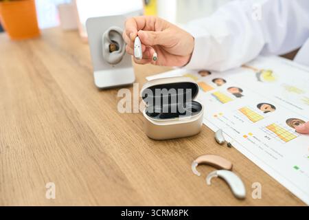 Audiologo con moderno apparecchio acustico alla reception della clinica Foto Stock