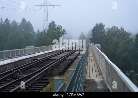 Ammira i binari ferroviari dalla cima dello storico ponte ferroviario Jyranko a Heinola, Finlandia, in una mattinata nebbiosa. Foto Stock