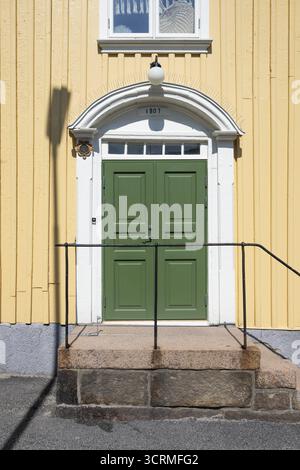 Ingresso di una casa di legno giallo chiaro con porta verde e telaio bianco, Fjaellbacka, Bohuslaen, Svezia occidentale, Svezia Foto Stock