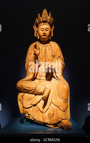 Singapore: Una statua in legno di salice di un Guanyin seduto, dinastia Ming (1368 - 1644) Cina, Museo delle civiltà Asiatiche, Palazzo dell'Imperatrice. Guanyin, abbreviazione di Guanshiyin, è un bodhisattva nel buddismo Mahayana spesso associato alla compassione e alla misericordia. Anche se è spesso ritratta come una donna, è al di là del genere e può essere raffigurata sia come maschio che come femmina. Guanyin è spesso definita la "divinità buddista più amata", a causa dei suoi poteri miracolosi e della sua amorevole compassione. Non è venerata solo nel buddismo, ma anche nel taoismo e nella religione popolare cinese, con varie storie Foto Stock