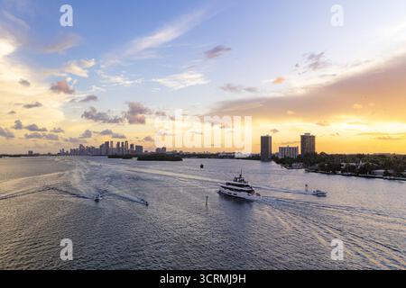 Vista aerea degli yacht che attraversano le scintillanti acque della baia di Biscayne sotto un cielo abbronzato di ardenti tonalità del tramonto, Miami, Florida, Stati Uniti. Foto Stock
