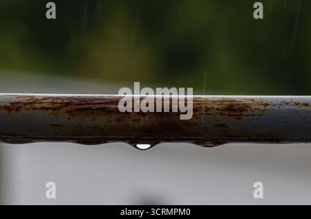 Ringhiera grigia con gocce di pioggia e ruggine, vista della terrazza catturata con profondità ridotta per uno sfondo morbido e morbido. Foto Stock