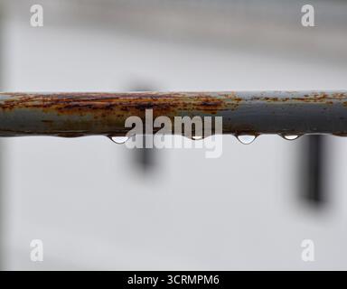 Vista artistica del bar grigio orizzontale corroso sulla terrazza con gocce di pioggia fresca, sfondo intenzionalmente sfocato. Foto Stock