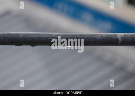 Dopo la pioggia: Le goccioline allineano una ringhiera grigia arrugginita, con lo sfondo che cade via con una messa a fuoco morbida. Foto Stock
