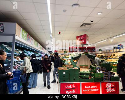 Manchester, Regno Unito - 25 settembre 2025: I clienti acquistano frutta e verdura mentre le esposizioni promuovono offerte speciali settimanali e sconti. Foto Stock