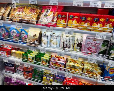 Manchester, Regno Unito - 25 settembre 2025: Pacchetti di snack colorati sugli scaffali dei supermercati in un negozio di alimentari, che mostrano varietà e prezzi. Foto Stock