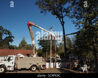 Equipaggi delle compagnie elettriche che riparano i danni causati da un albero caduto. Pali di servizio sostituiti da equipaggi. Dumper a benna per attrezzature pesanti. Foto Stock
