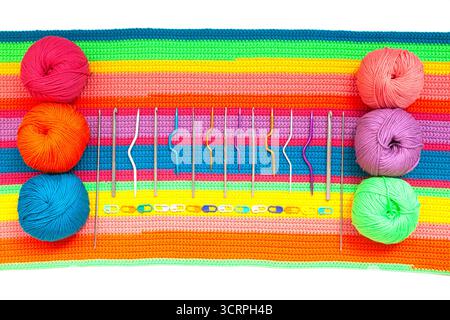 Tutto per maglieria a mano. Tessuto lavorato a maglia multicolore realizzato a mano con sfere di fili multicolori, spille e vari aghi per maglieria. Foto Stock