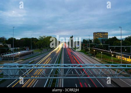 Sentieri leggeri sull'autostrada A12 vicino a Zoetermeer durante il crepuscolo, con traffico mattutino nella conurbazione urbana di Randstad, Paesi Bassi. Foto Stock