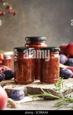 Salsa chutney fatta in casa in tre vasetti di vetro - assapora prugne, mele, cipolle e spezie Foto Stock
