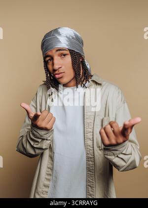 Giovane uomo con un abbigliamento casual e durag che posa con fiducia. Foto Stock