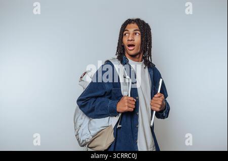 Giovane con zaino e tablet che sembra sorpreso. Foto Stock