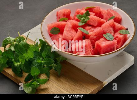 Piatto pieno di anguria a dadini guarnita con menta fresca. Vista dall'alto. Perfetto per i menu e le ricette estivi Foto Stock