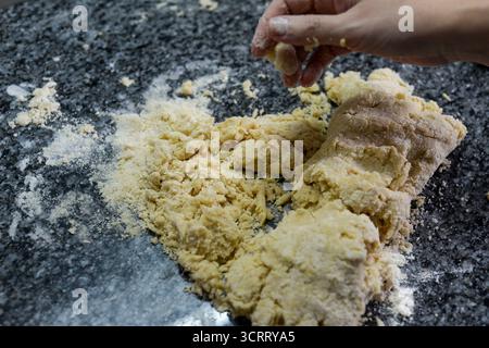 Impastare l'impasto fatto in casa su un piano di lavoro infarinato per creazioni gustose Foto Stock