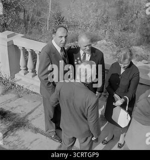 Un'autentica fotografia d'archivio in bianco e nero del 1960 mostra un gruppo di funzionari e un veterano di guerra decorato a Sviatohirsk (allora Slavyanogorsk), RSS Ucraina. L'incontro si svolge su una terrazza all'aperto di un sanatorio o una "casa di riposo" nella famosa località turistica. Gli uomini e le donne sono impegnati in una conversazione rilassata ma formale. La presenza di un veterano della grande Guerra Patriottica (seconda guerra mondiale), la sua tuta decorata con medaglie, indica un evento ufficiale o commemorativo. Si tratta di un sincero assaggio della vita sociale delle figure rispettate dell'Unione Sovietica Foto Stock