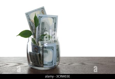 Vaso di vetro con dollari, germogli e monete su un tavolo di legno su sfondo bianco Foto Stock