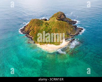 Vista aerea della vivace e verde isola di Popoia circondata dall'oceano turchese, con onde spumose che si infrangono sulla sua spiaggia sabbiosa, Honolulu, Hawaii, Stati Uniti. Foto Stock