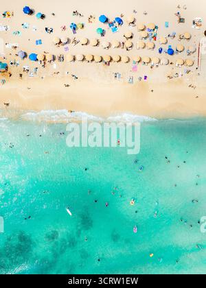 Vista aerea delle morbide sabbie dorate che incontrano il vibrante mare turchese, punteggiato di ombrelloni e ombrelloni colorati lungo la spiaggia, Waikiki Beach, Honolulu, Hawaii, Stati Uniti. Foto Stock