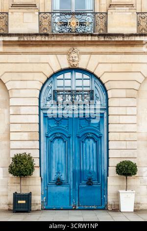 Parigi, Francia - 7 settembre 2025: Porta blu ornata su Place Vendôme con architettura classica e alberi in vaso Foto Stock