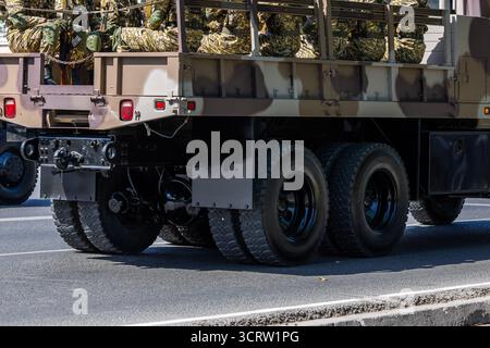 Più soldati con uniformi mimetiche siedono sul retro di un camion militare prima della parata militare. Foto Stock