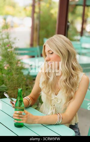 Giovane donna che usa lo smartphone in un bar all'aperto Foto Stock