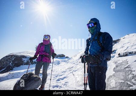Gli escursionisti si fermano mentre scendono dalla cima di una montagna ghiacciata in una giornata di uccelli rossi Foto Stock