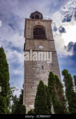 Torre dell'orologio della Chiesa della Santissima Trinità a Bansko, Bulgaria, storico campanile in pietra sotto il suggestivo cielo nuvoloso. Foto Stock