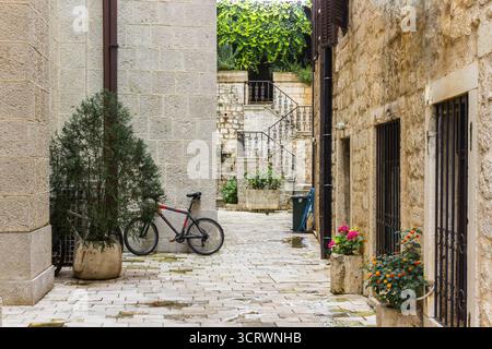 Bicicletta di montagna appoggiata su un muro di pietra nella città vecchia di Cattaro, Montenegro. Stradina storica dall'architettura medievale Foto Stock