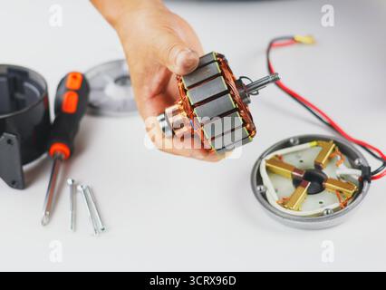 Questa immagine mostra lo smontaggio o la riparazione di un motore elettrico, probabilmente proveniente da un apparecchio elettrico o da una piccola macchina. Il rotore (indotto) con rame Foto Stock