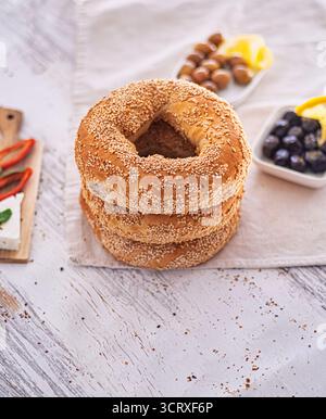 Su un panno beige morbido viene posta una pila di tre simits di crosta di sesamo (bagel turchi). L'ambiente tradizionale della colazione turca. Messa a fuoco selettiva. Foto Stock