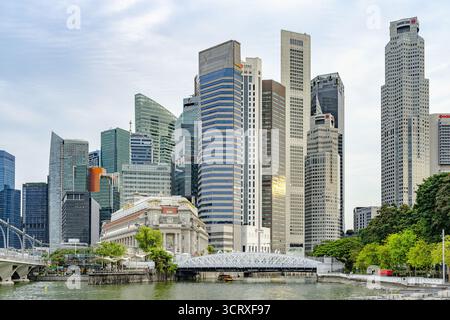 Vista di un paesaggio urbano moderno con grattacieli scintillanti riflessi nelle acque tranquille, un ponte che collega il vibrante paesaggio urbano di Singapore. Foto Stock