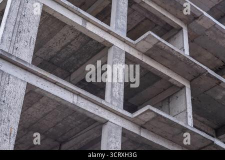 Struttura in cemento non finita. Vista ravvicinata di un edificio in cemento non finito con travi esposte e superfici grezze. Foto Stock