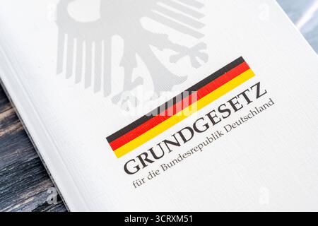 Baviera, Germania - 3 ottobre 2025: La legge fondamentale della Repubblica federale di Germania come libro stampato con aquila federale e bandiera tedesca su un tavolo di legno *** Das Grundgesetz der Bundesrepublik Deutschland als gedrucktes Buch mit Bundesadler und deutscher Flagge auf einem Holztisch Foto Stock
