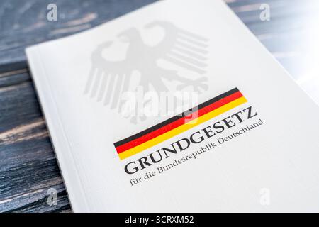 Baviera, Germania - 3 ottobre 2025: La legge fondamentale della Repubblica federale di Germania come libro stampato con aquila federale e bandiera tedesca su un tavolo di legno *** Das Grundgesetz der Bundesrepublik Deutschland als gedrucktes Buch mit Bundesadler und deutscher Flagge auf einem Holztisch Foto Stock