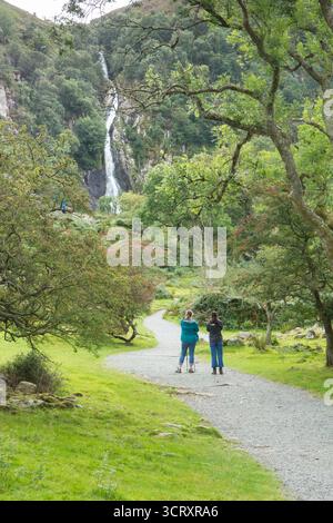 Due donne che camminano su un sentiero che guarda Aber Falls, Rhaeadr Fawr in lontananza, vestite con l'attrezzatura da trekking Foto Stock